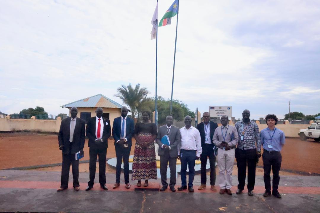 UNMISS delegation group photo at the South Sudan state government building in Warrap with national and UN flags